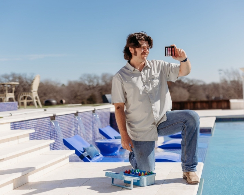 Man looking at his tool that measure pool water quality next to a pool.