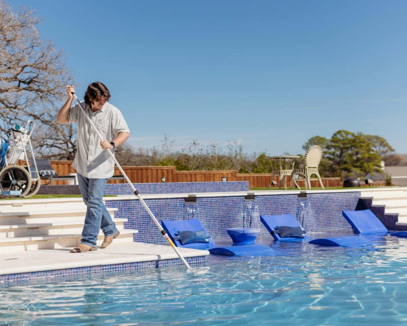 Pool cleaning and maintenance worker cleaning pool.