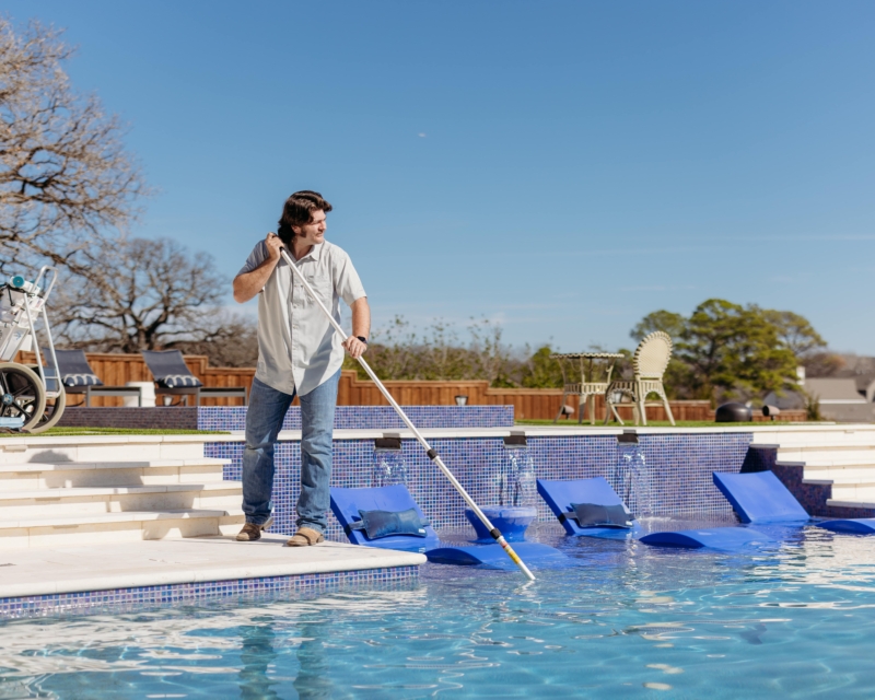 Pool cleaning and maintenance worker cleaning pool.